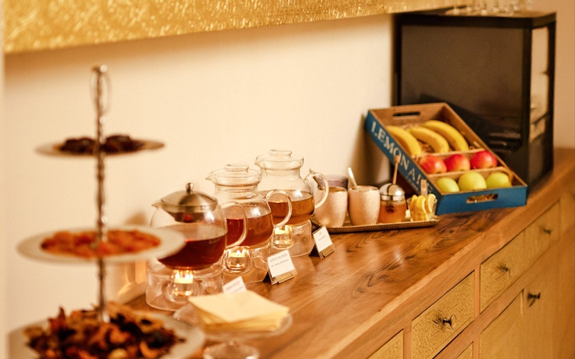 Tea setup with glass teapots, fruit, and snacks at Mandala Day Spa.