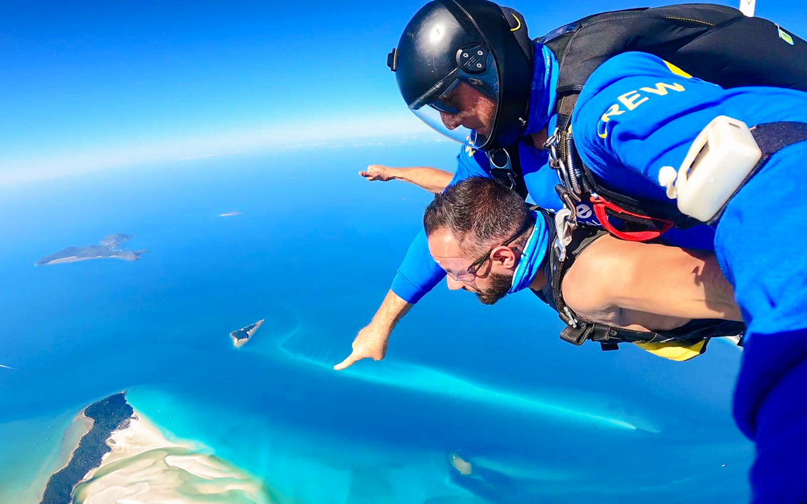 Tandem skydivers over Airlie Beach with Whitsunday Islands in view.