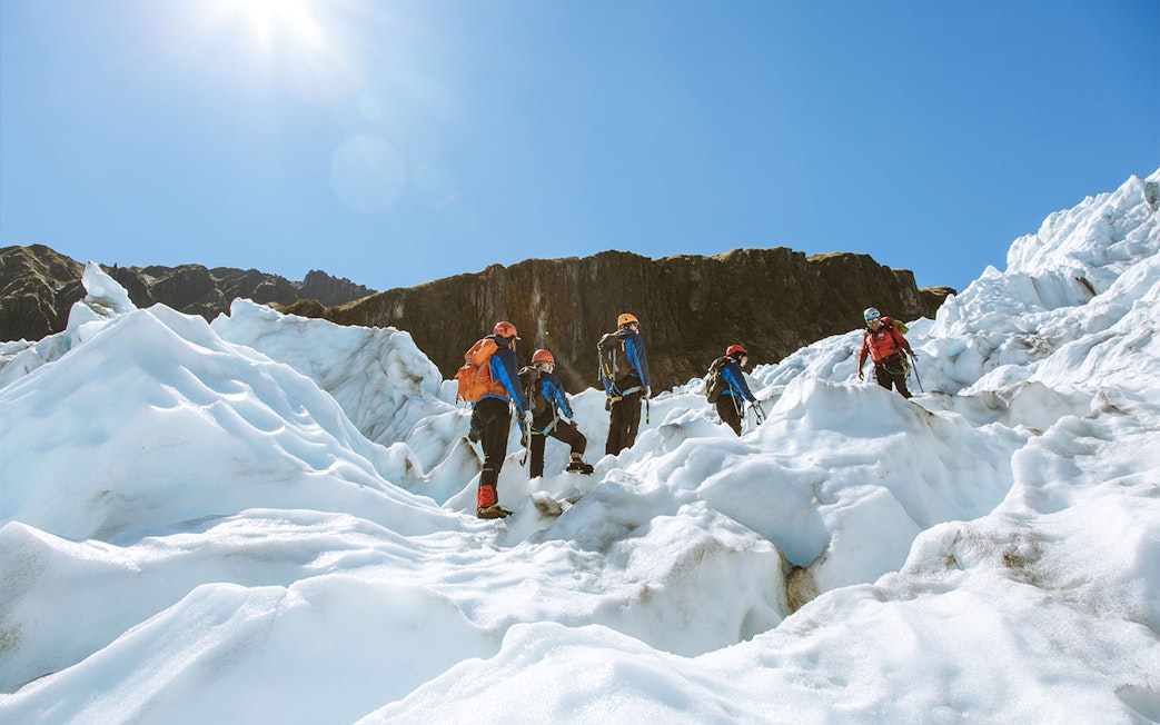Group climbing Fox Glacier with guide during heli ice climbing experience.