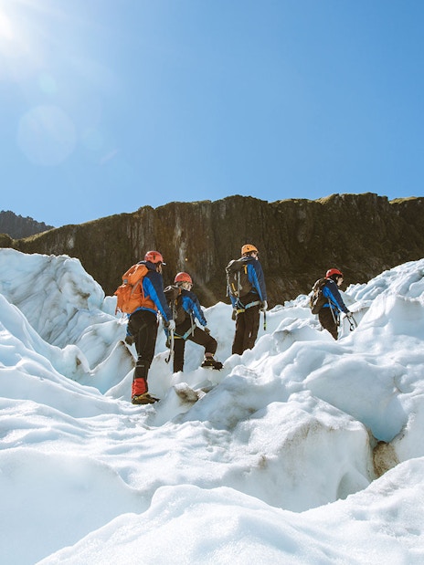 Group climbing Fox Glacier with guide during heli ice climbing experience.