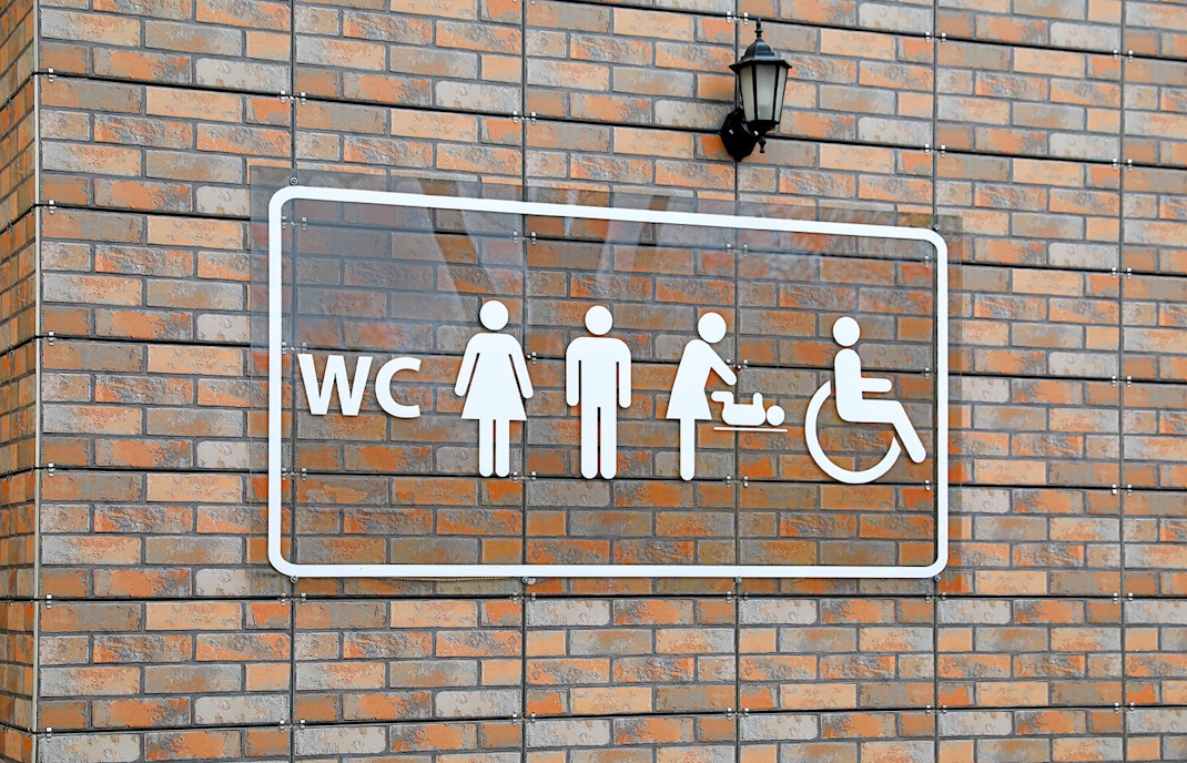 Public restroom sign with symbols for men, women, baby changing, and wheelchair access.