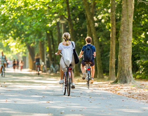 Children biking through Vondelpark, Amsterdam, on a sunny day.