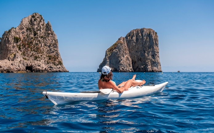 Kayaker near Faraglioni rocks in Capri, Italy.