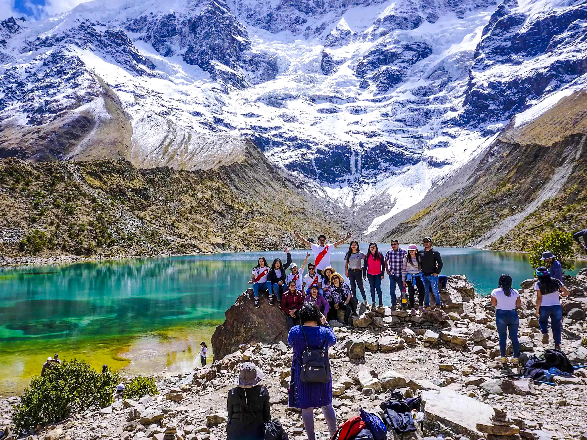 Group of hikers at Humantay Lake with snowy mountains, Cusco day hike.