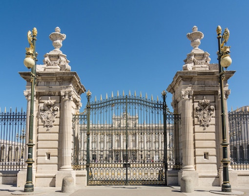 Royal Palace of Madrid entrance with tourists exploring the historic architecture.