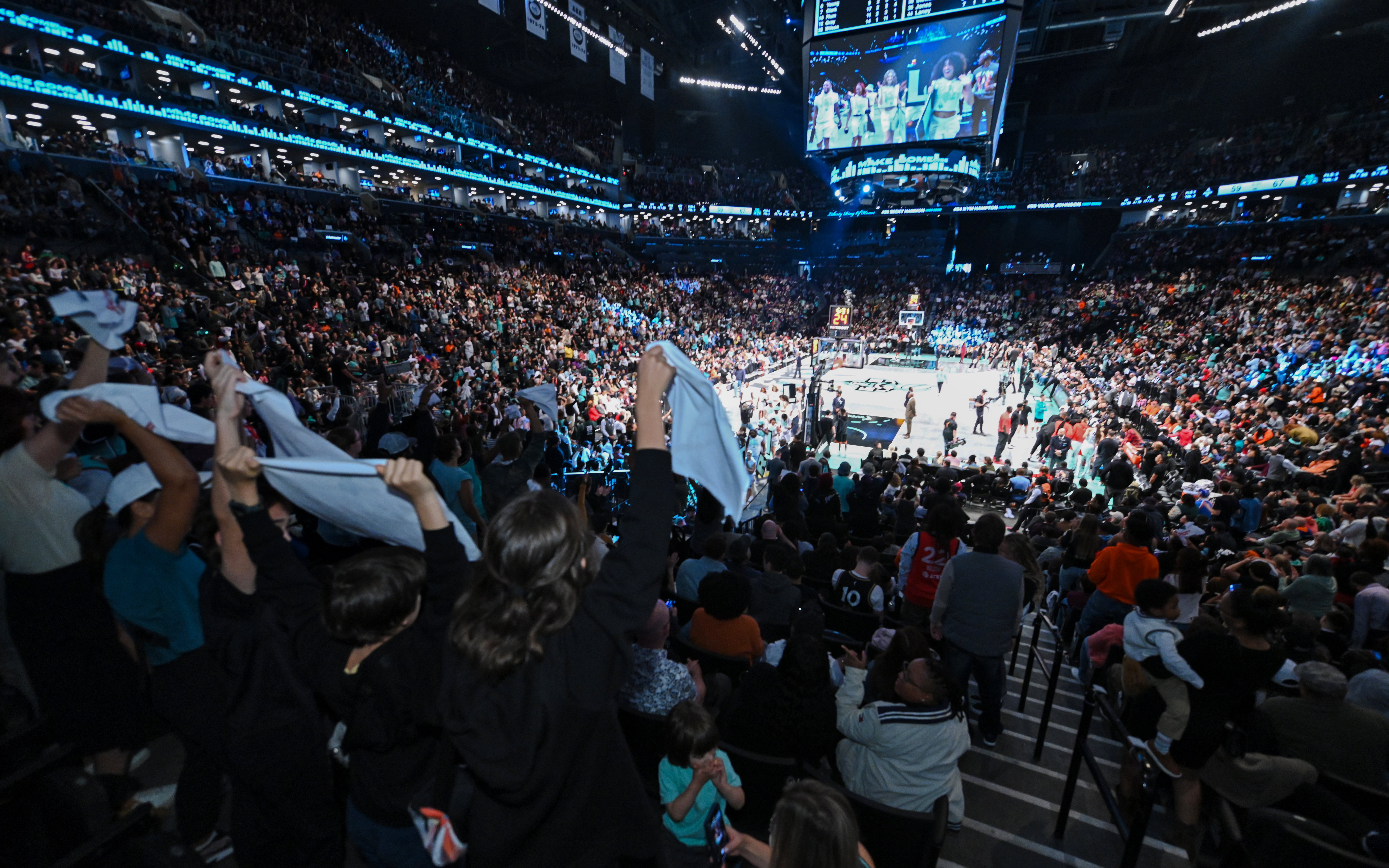 Fans cheering at New York Liberty basketball game in a packed arena.