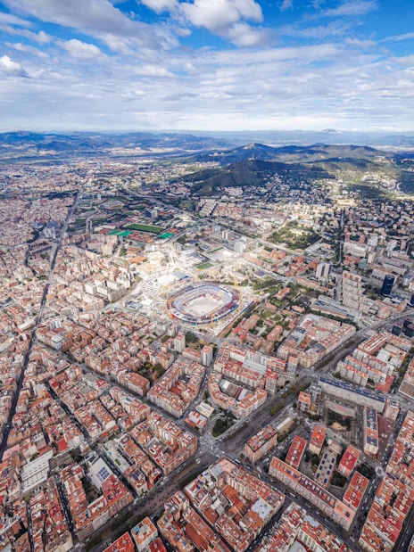 Aerial view of Barcelona cityscape with mountains in the background.
