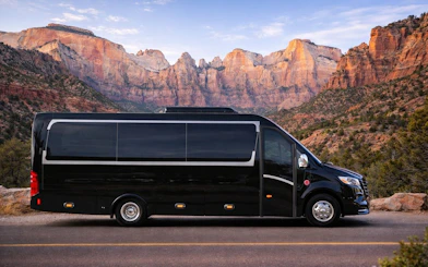 Luxury tour bus in Zion National Park with scenic canyon backdrop.