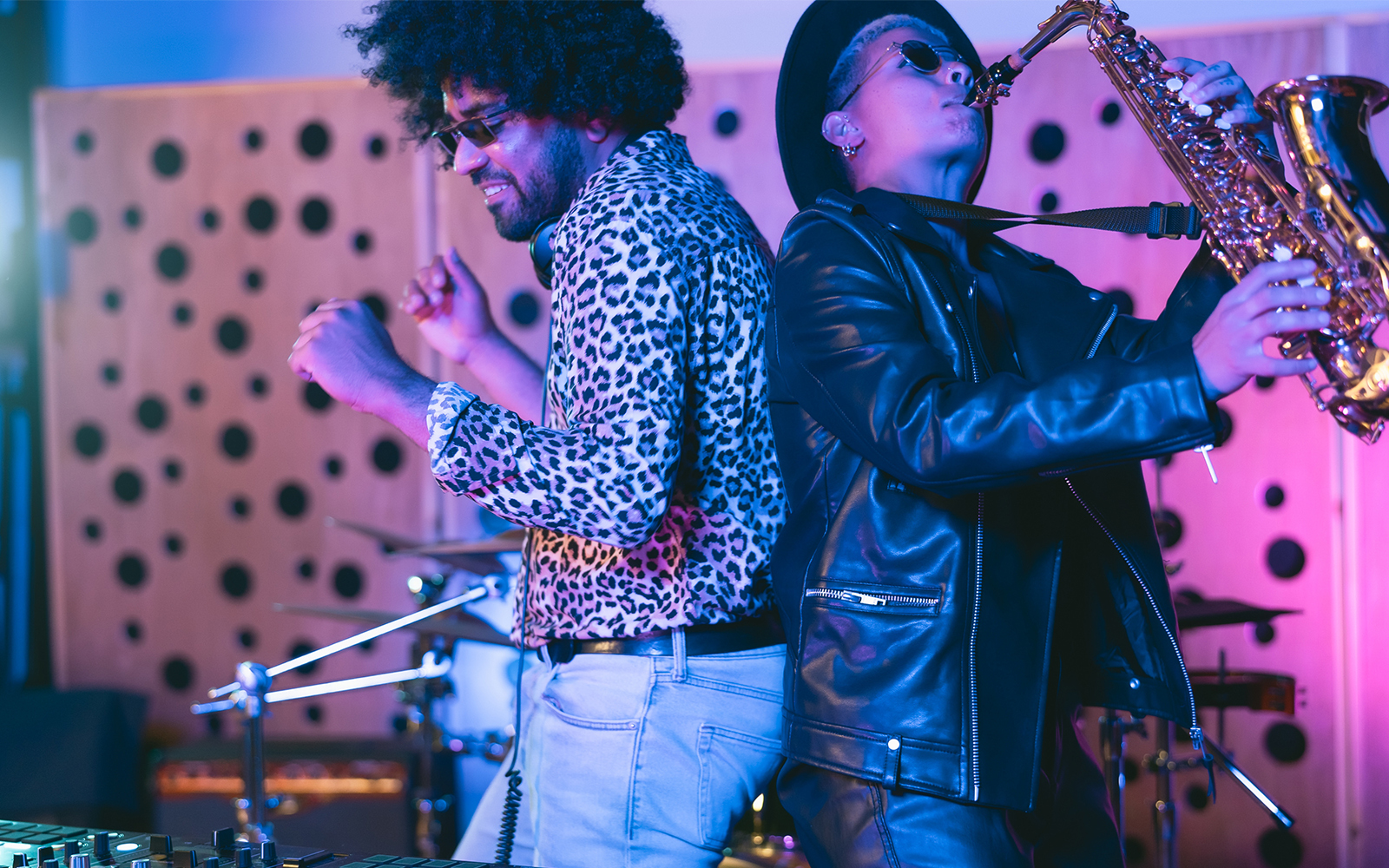 Young happy people playing music with dj mixer and saxophone in house studio