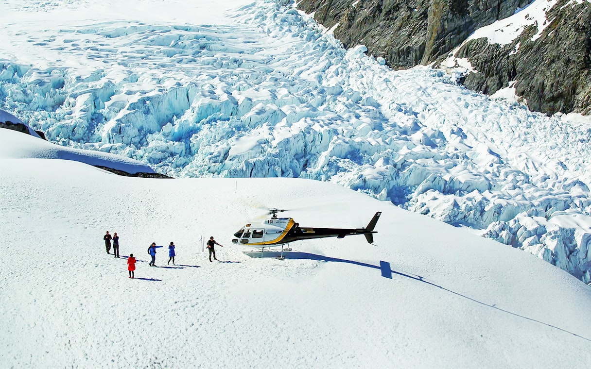 Helicopter landing with people on Fox Glacier, New Zealand, during scenic tour.