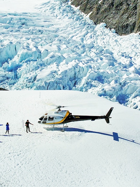 Helicopter landing with people on Fox Glacier, New Zealand, during scenic tour.