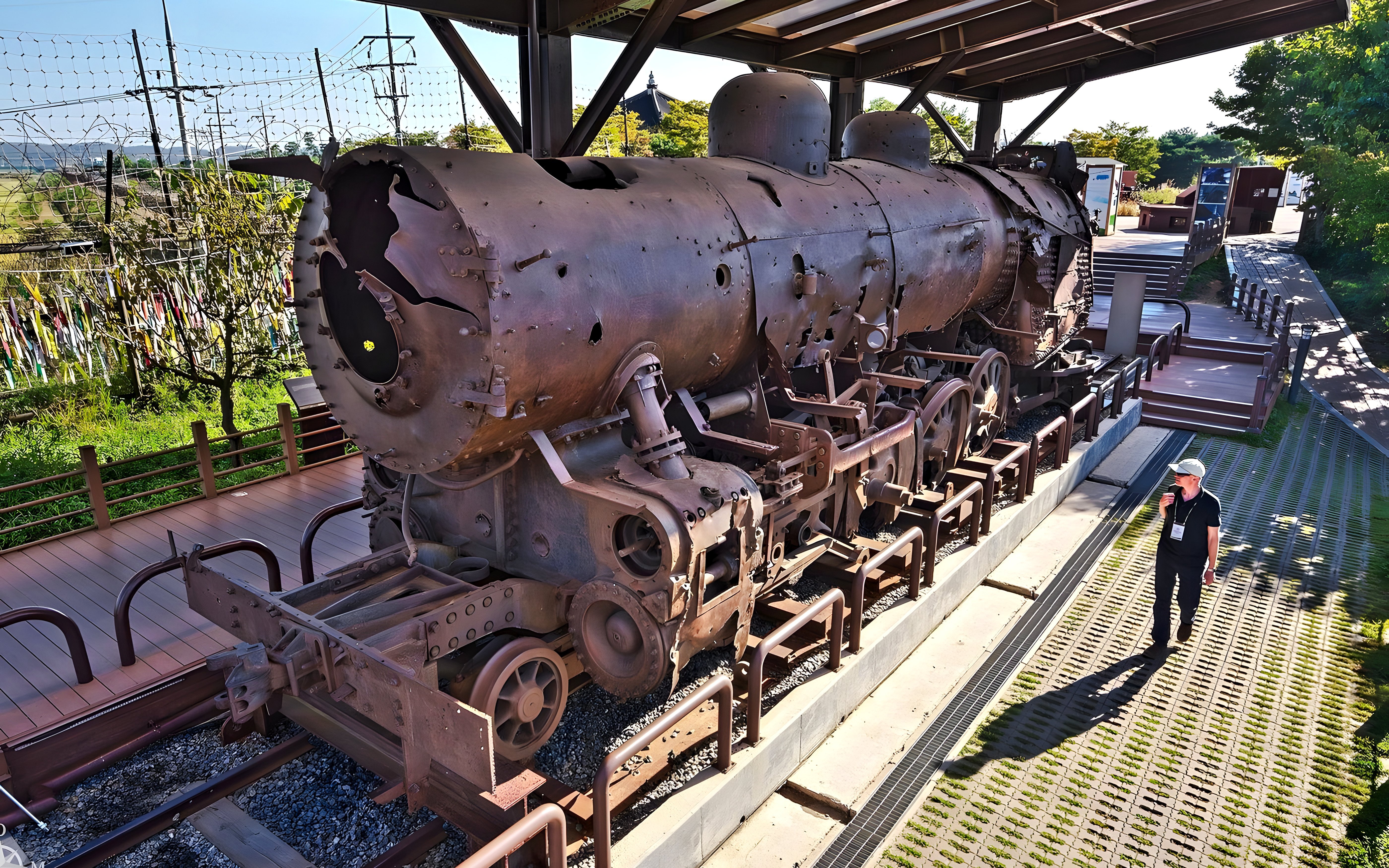 Rusty steam locomotive at DMZ, South Korea, with barbed wire fence in background.