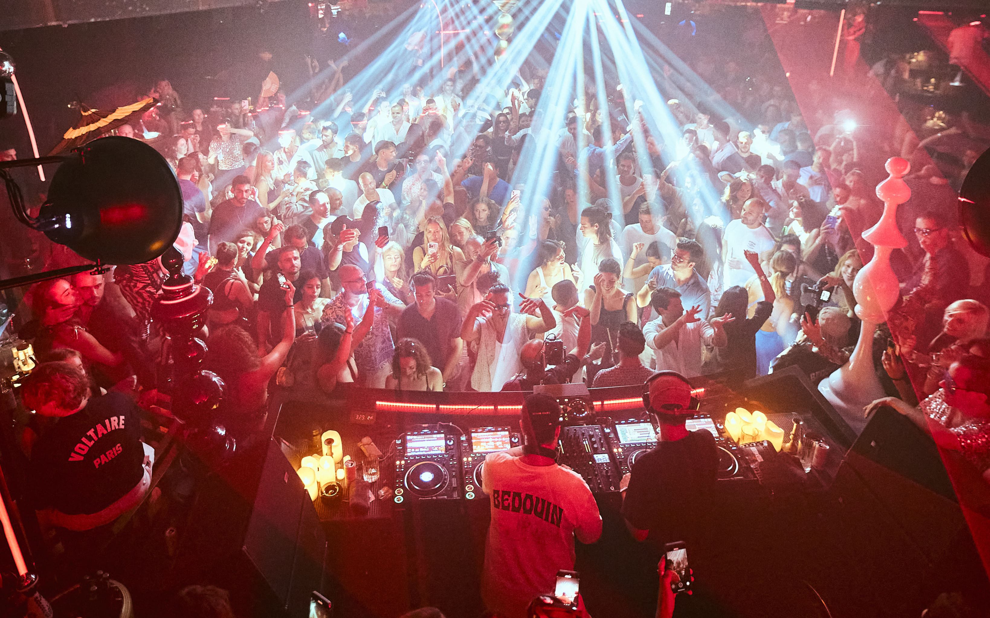 DJ performing at Club Chinois, Ibiza with crowd dancing under vibrant lights.