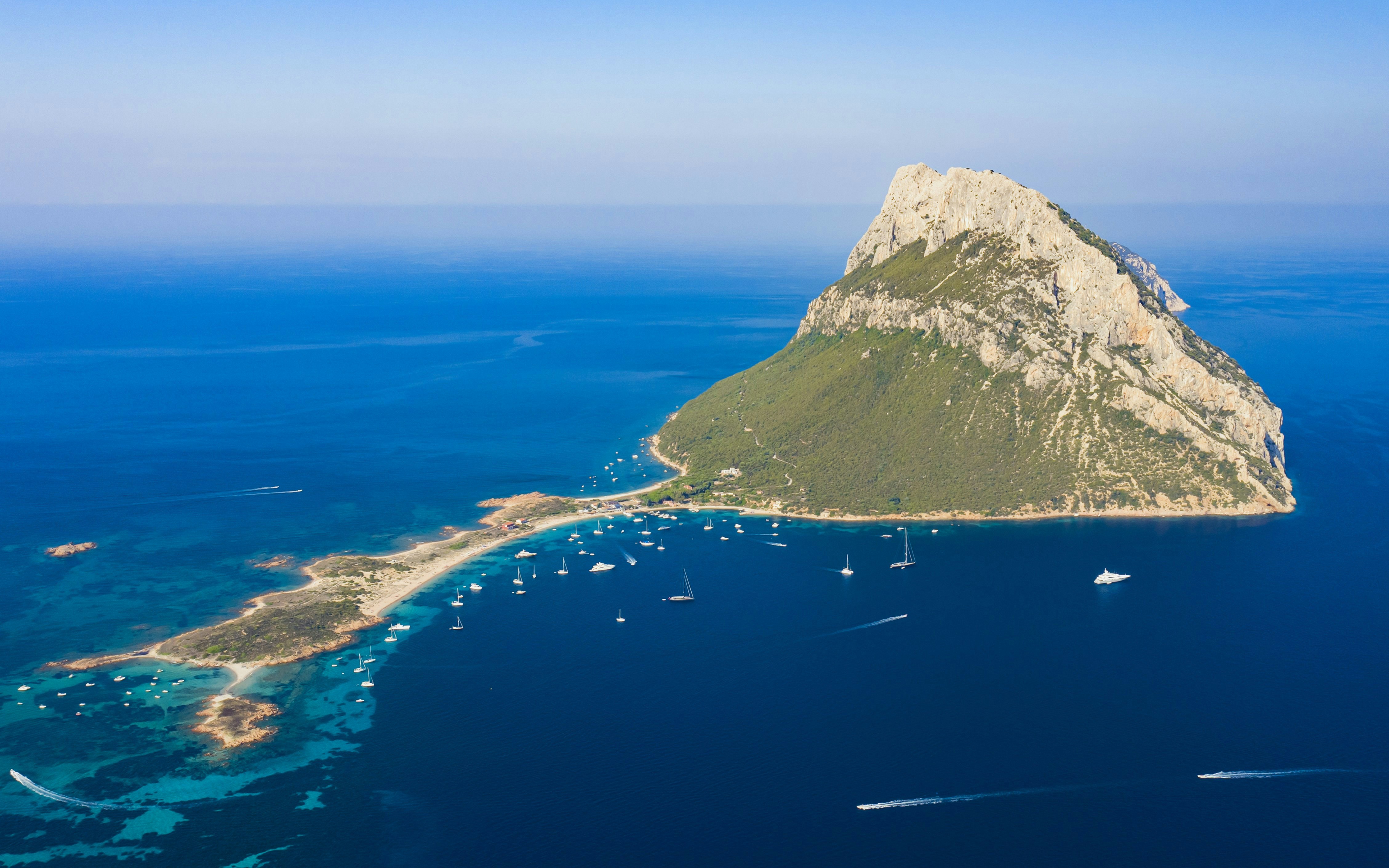 Aerial view of Tavolara Island in the marine reserve with boats in the surrounding blue waters.