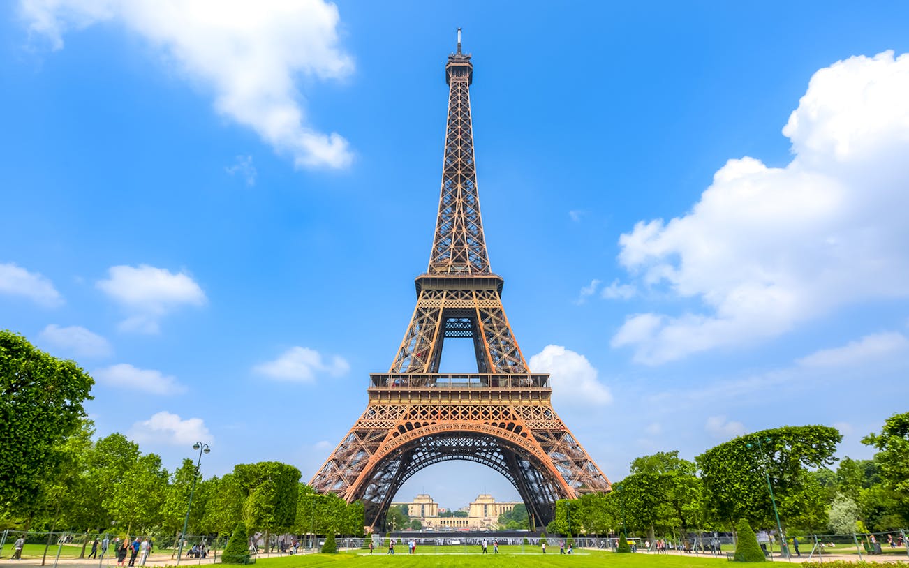 Eiffel Tower in Paris with green park and blue sky.