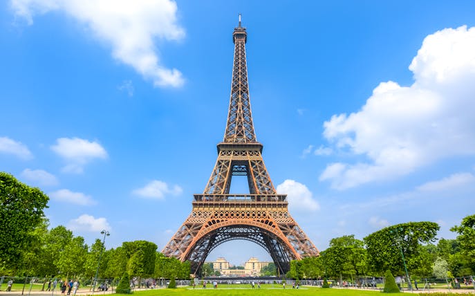 Eiffel Tower in Paris with green park and blue sky.