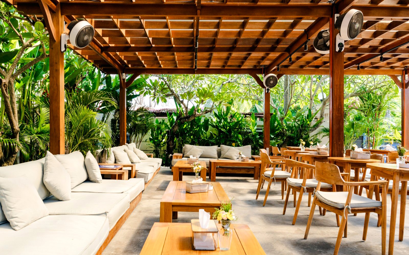 Outdoor seating area with wooden furniture and lush greenery on West Nusa Penida Island tour.