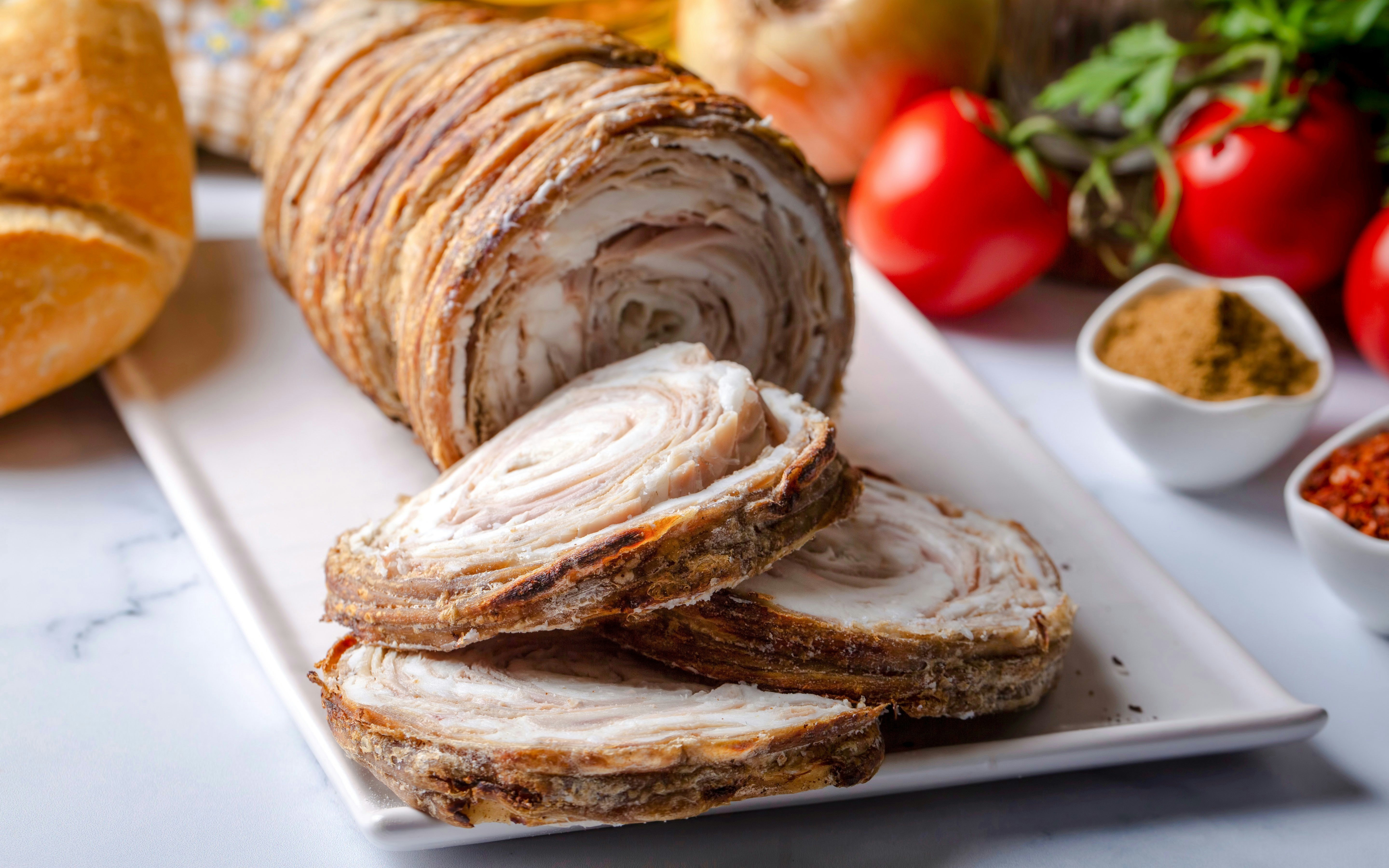 Kokoretsi dish served at Delphi Restaurant with fresh ingredients in the background.