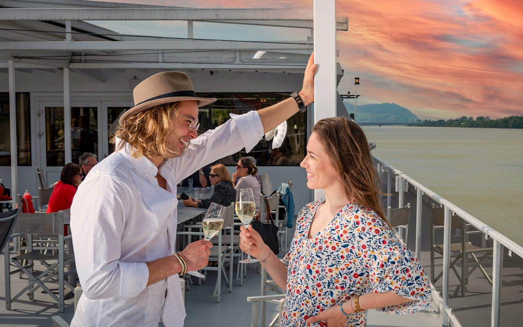 Couple enjoying drinks on a Wachau cruise from Vienna at sunset.