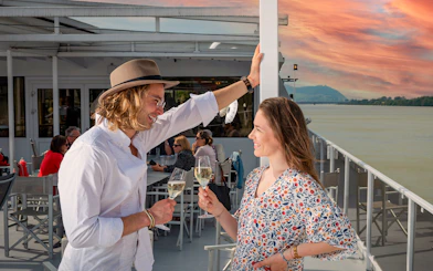Couple enjoying drinks on a Wachau cruise from Vienna at sunset.