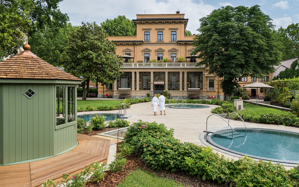 Visitors in robes walking by pools at QC TermeTorino Spa and Resort, Italy.