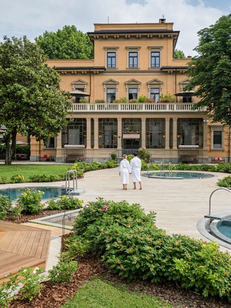 Visitors in robes walking by pools at QC TermeTorino Spa and Resort, Italy.