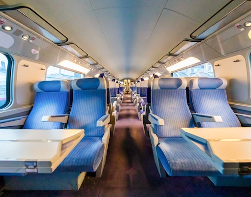 Train interior from Paris with blue seats and tables.
