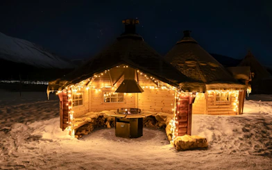 Cozy wooden cabin with lights in snowy Tromso, Norway, part of Northern Lights and Sami tour.