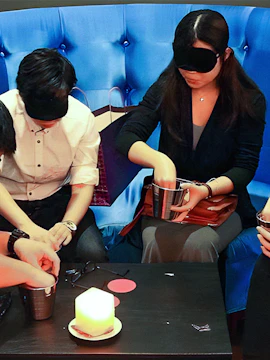 People wearing blindfolds participating in a Dining in the Dark experience.