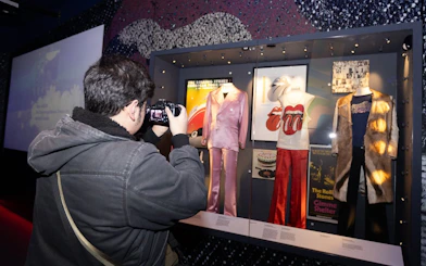 Visitor photographing Rolling Stones exhibit at The British Music Experience.