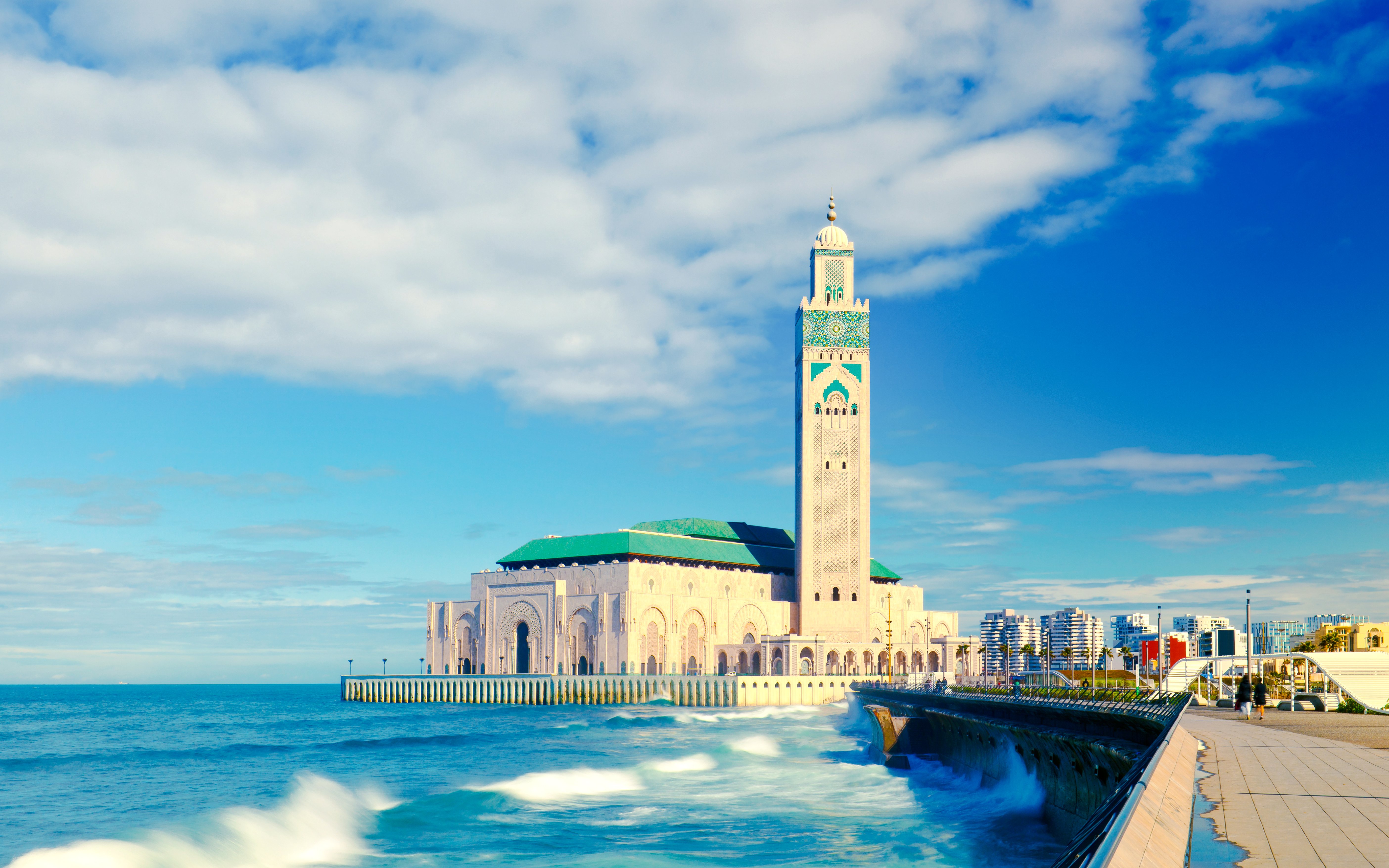 Hassan II Mosque in Casablanca with ocean waves in the foreground.
