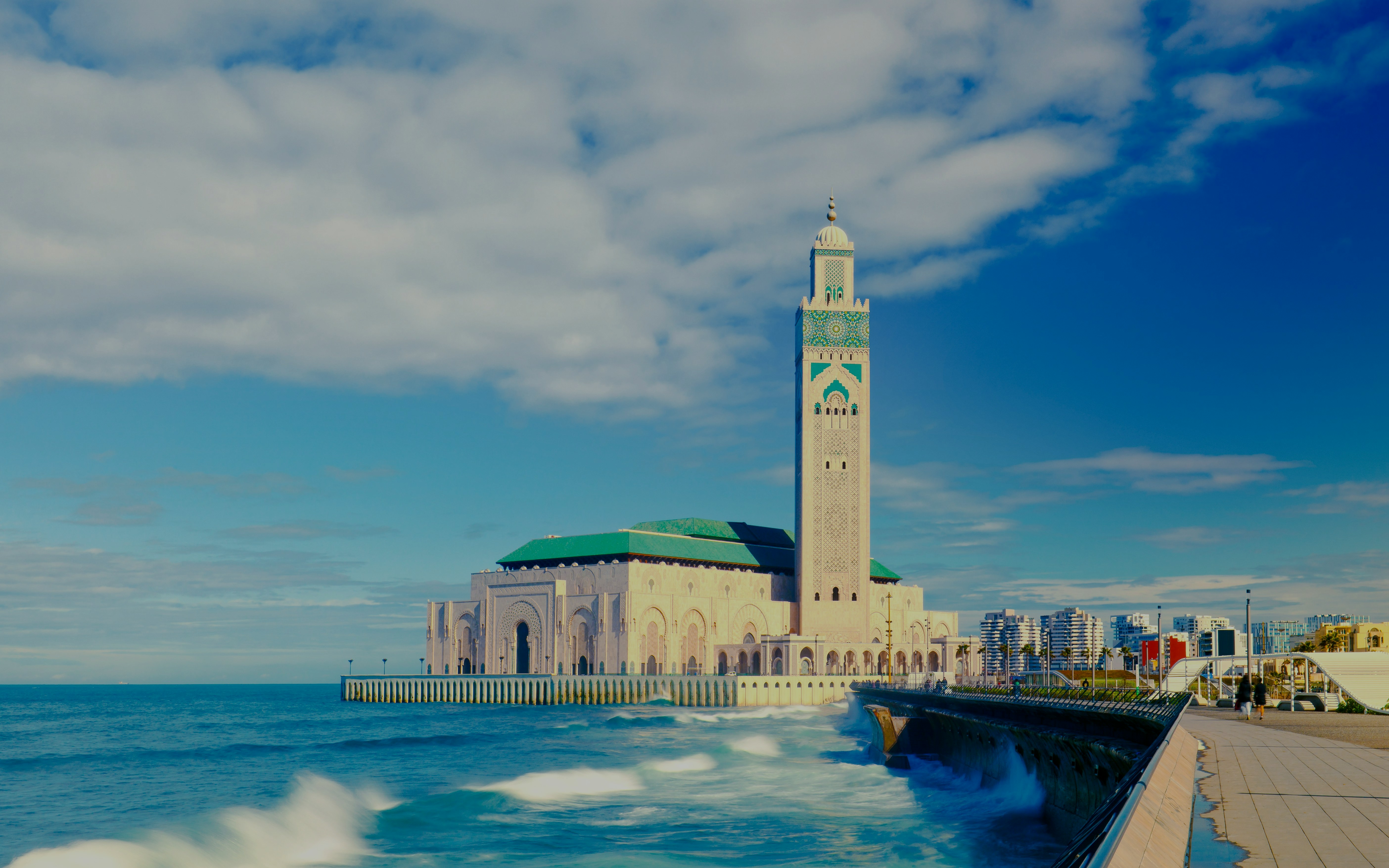 Hassan II Mosque in Casablanca with ocean waves in the foreground.