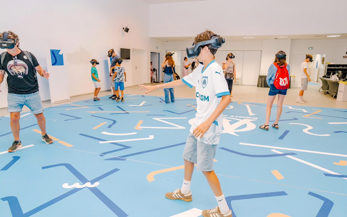 Visitors experiencing virtual reality at Velodrome stadium tour.