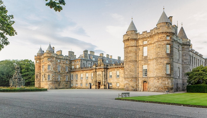 Tourists at Palace of Holyroodhouse entrance, London, with multimedia guide.