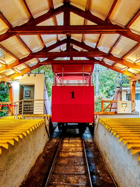 Santiago cable car station with red car and wooden beams.