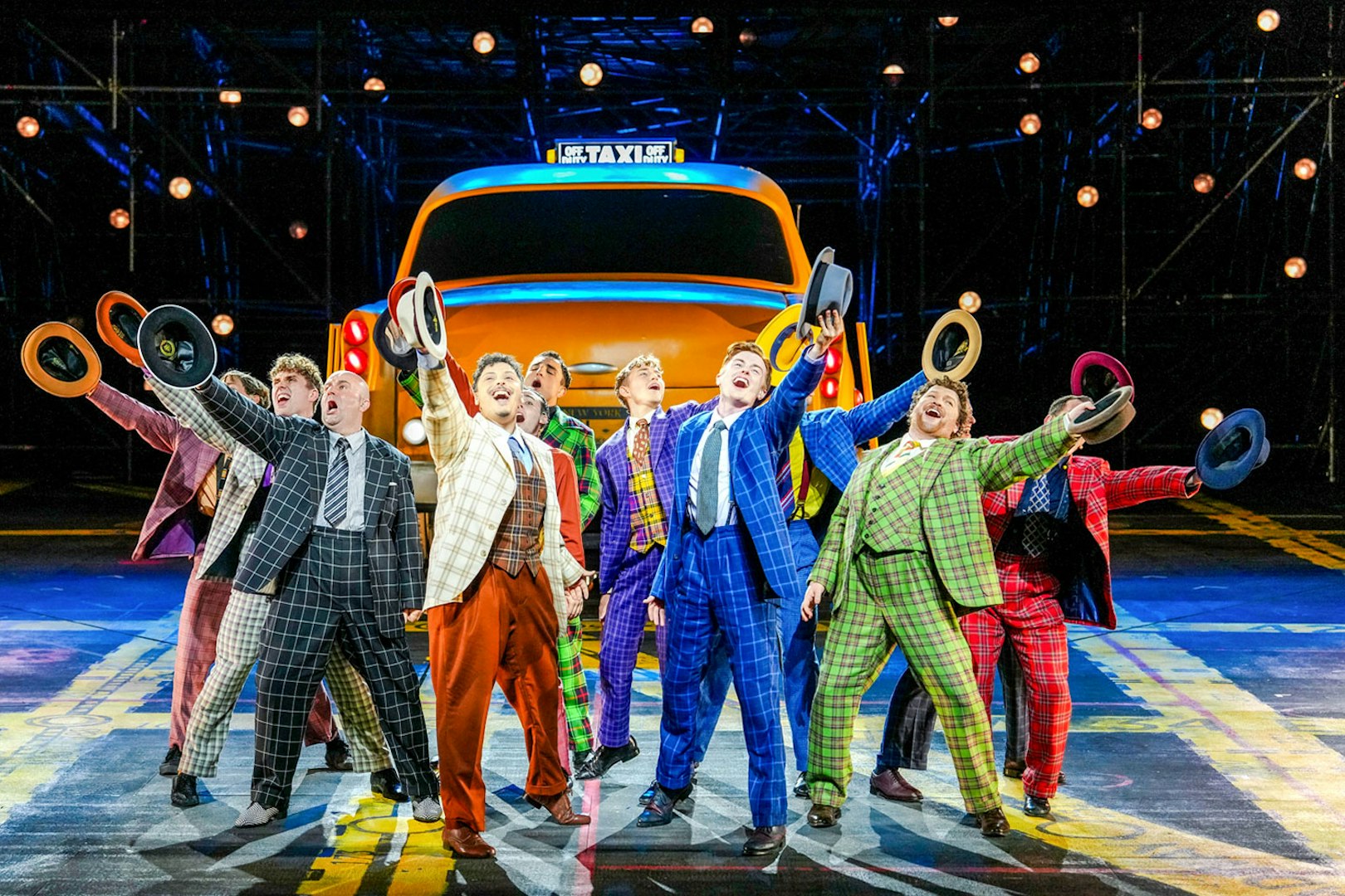 Performers in colorful suits holding hats in front of a taxi during "Guys & Dolls" on Sydney Harbour.