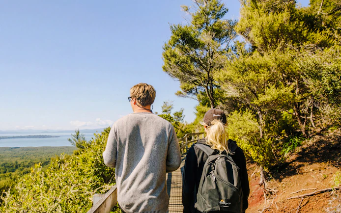 Visitors walking on a trail with views of Rangitoto Island, Auckland.
