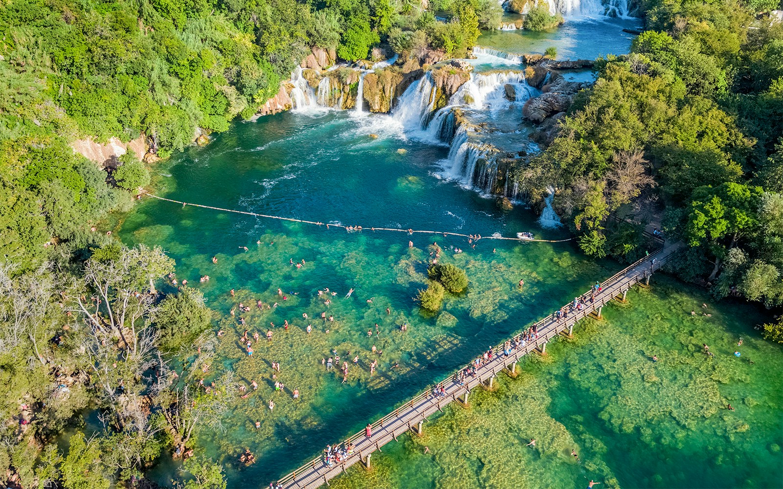 Aerial view of Krka waterfall and bridge with visitors swimming at Krka National Park, Croatia.