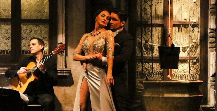 Tango dancers performing at Aljibe Tango Show in Buenos Aires with guitarist in background.
