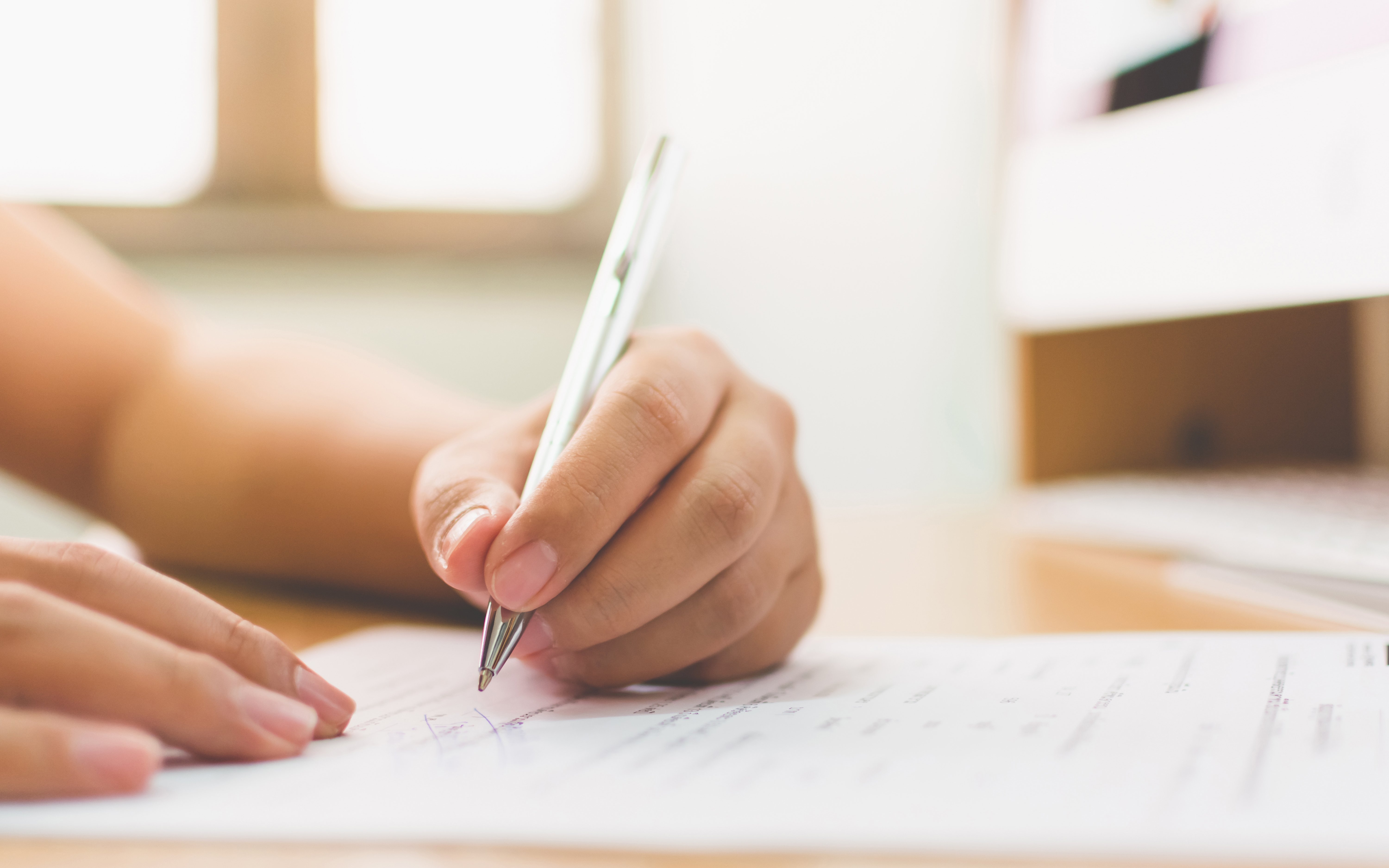 Signing a waiver form with a pen on a desk.