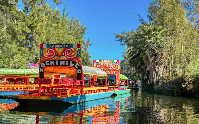 Trajinera boats on Xochimilco canal, Mexico City, with colorful decorations.