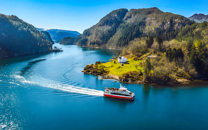 Cruise boat on Mostraumen Fjord near Bergen with scenic mountain views.
