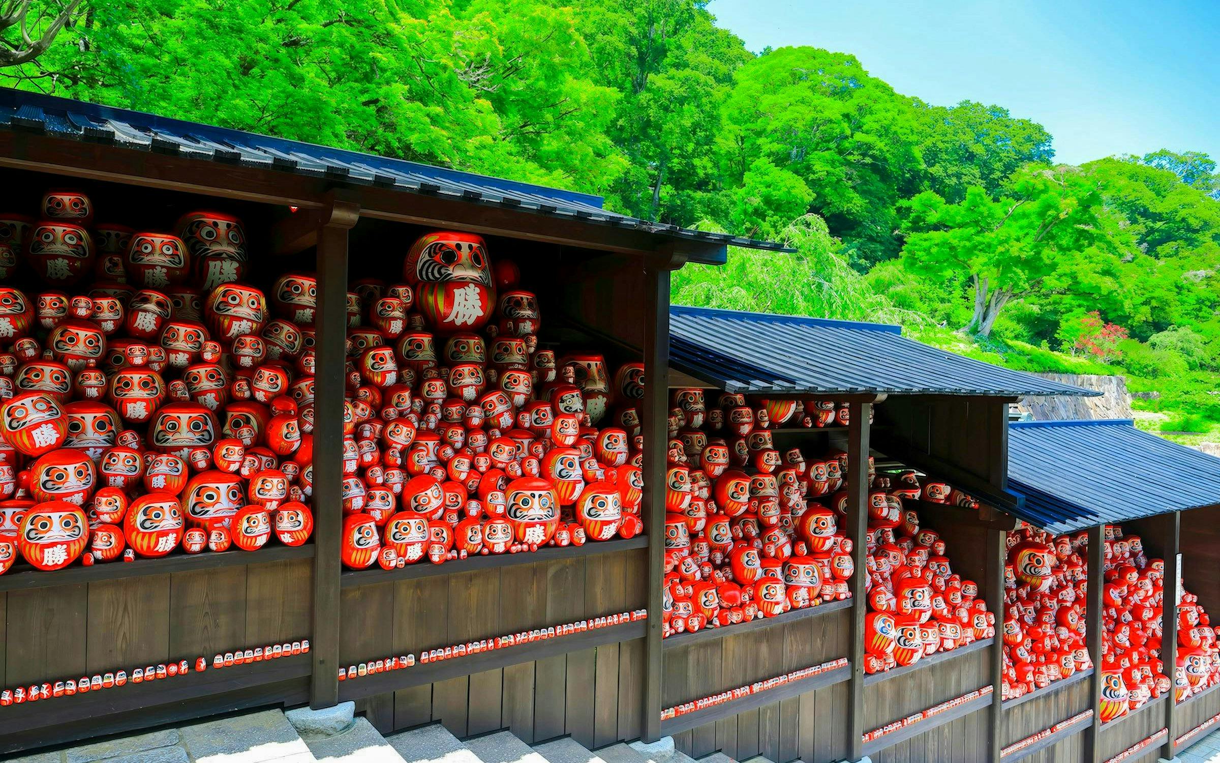Daruma dolls displayed in wooden stalls, symbolizing perseverance in Japan.