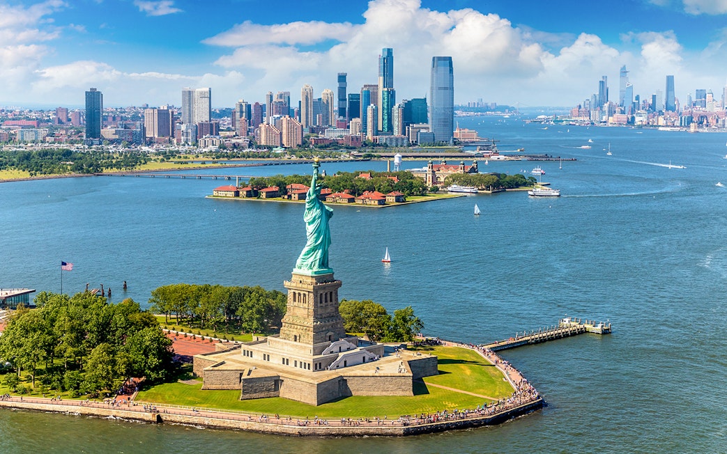 Statue of Liberty with New York City skyline during helicopter tour.