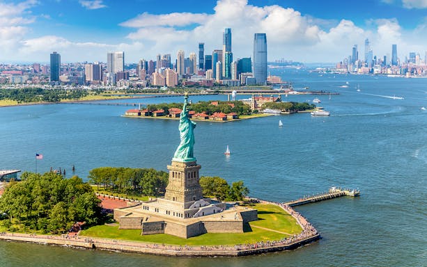 Statue of Liberty with New York City skyline during helicopter tour.