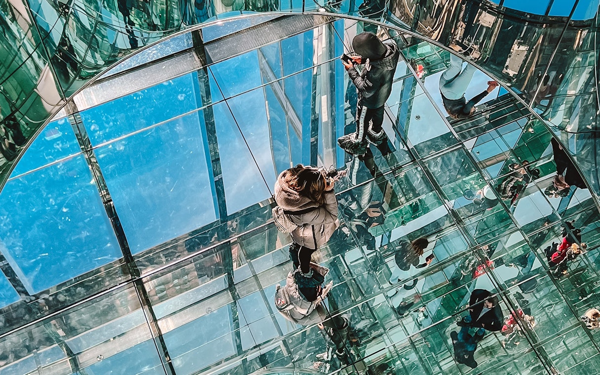 Visitors walking on glass floor at SUMMIT One Vanderbilt, New York City.