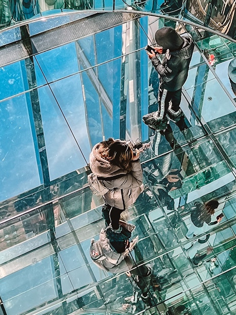 Visitors walking on glass floor at SUMMIT One Vanderbilt, New York City.