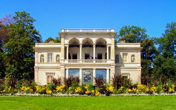 Neoclassical villa with statues and gardens in Geneva.