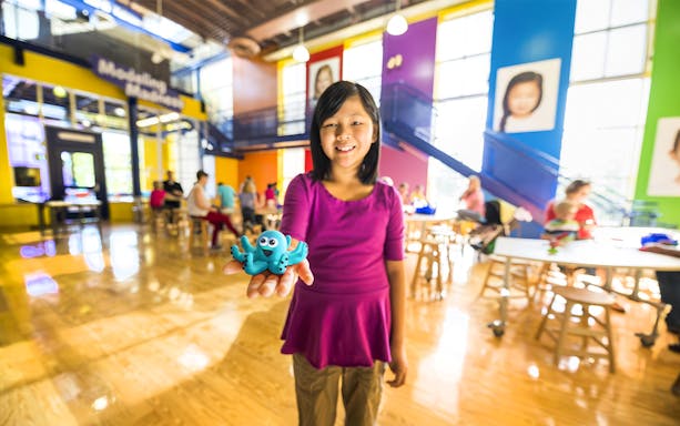 Child holding a blue clay octopus at Crayola Experience in Orlando.