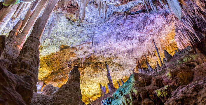 Stalactites and stalagmites inside Hams Caves, Mallorca, with colorful lighting.